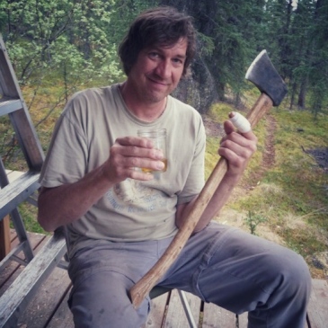 Photo of a guy with an axe, a bandaged thumb, and a glass of scotch